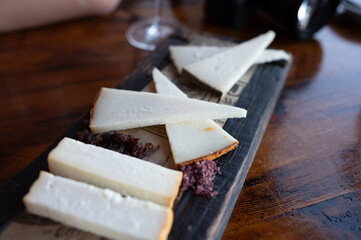 Tasting of Spanish cheeses made on Canary islands, goat cheese, smoked and triangles of manchego curado cheese on wooden plank