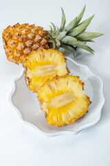 Two whole fresh ripe pineapples or sweet baby ananas on white background close up