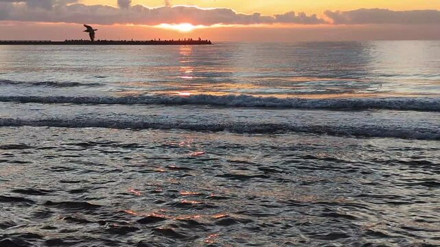 &Agrave; l&rsquo;aube, le soleil se l&egrave;ve lentement au-dessus de l&rsquo;horizon et baigne la mer d&rsquo;une lumi&egrave;re dor&eacute;e. Les reflets rouges font allusion &agrave; la chaude journ&eacute;e d&rsquo;ao&ucirc;t &agrave; venir.