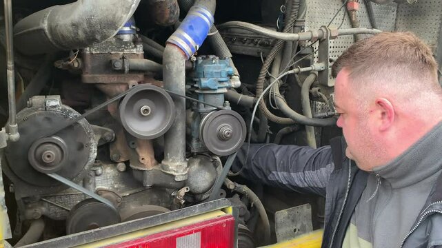 The worker services the engine of the car. Vehicle servicing mechanic inspects running engine.
