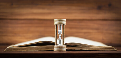 Hourglass with an old book. Time is passing, storytelling banner or background with copy space.