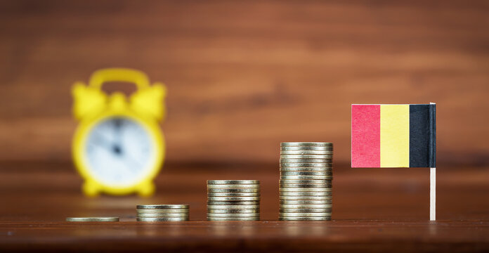 Coins with Belgium flag and alarm clock. Economy, financial or retirement savings and planning background.