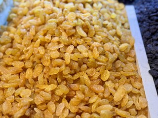 Close-up of a large mound of sun-dried yellow raisins laid out on a tray for sale at a farmer's market in Uzbekistan