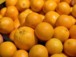 A box of ripe, fresh yellow oranges is for sale on the shelf of a fruit supermarket. Close-up