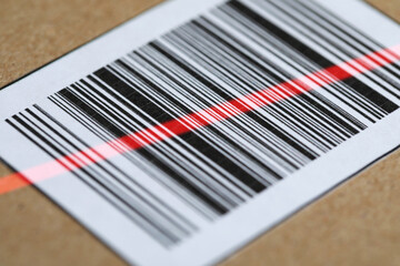 Parcel with label, closeup. Red laser light on barcode for scanning