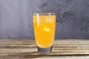 Sweet soda water with ice cubes in glass on wooden table