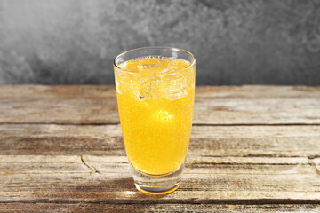 Sweet soda water with ice cubes in glass on wooden table, closeup