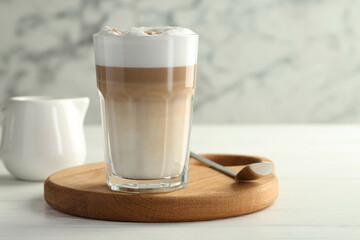 Tasty latte macchiato in glass on white wooden table, closeup