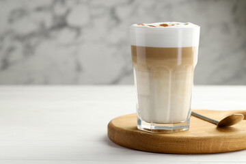 Tasty latte macchiato in glass on white wooden table, closeup. Space for text