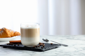 Tasty latte macchiato in glass on marble table, space for text. Coffee drink