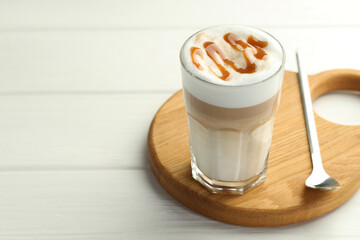 Tasty latte macchiato in glass on white wooden table, closeup. Space for text
