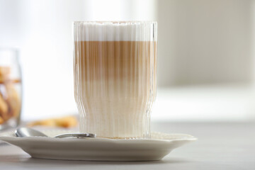 Tasty latte macchiato in glass on white table, closeup. Coffee drink