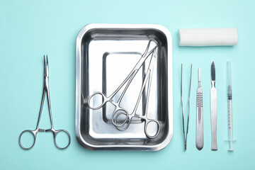 Different surgical tools on turquoise background, flat lay