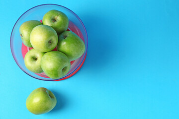 Kitchen scale with apples on light blue background, top view. Space for text