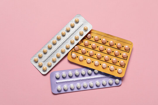 Blisters of oral contraceptive pills on pink background, flat lay