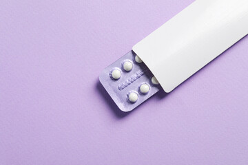 Blister of contraceptive pills in package on lilac background, top view. Space for text