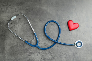 Cardiology. Stethoscope and red decorative heart on gray textured background, flat lay