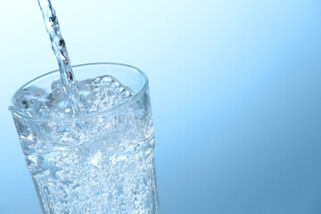 Pouring soda water into glass on light background, closeup. Space for text