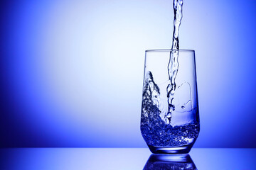 Pouring refreshing soda water into glass on blue background, closeup. Space for text