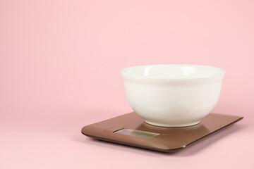 Electronic kitchen scale with bowl on pink background. Space for text