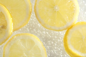 Soda water with lemon slices as background, closeup