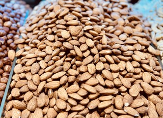 Delicious roasted almonds with spices are sold in large quantities at the vegetable market. Close-up
