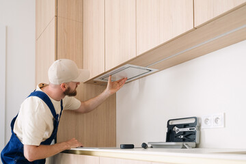 Professional handyman installs modern kitchen cabinet in residential apartment