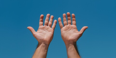 A pair of open hands are raised towards the bright blue sky, symbolizing freedom, aspiration, and the connection between humanity and nature's beauty.