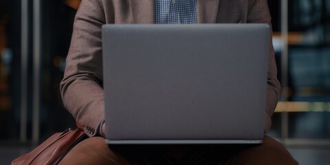 A businessman is seated with a laptop in a contemporary setting, illustrating the pivotal role of technology in today’s fast-paced professional and personal environments.
