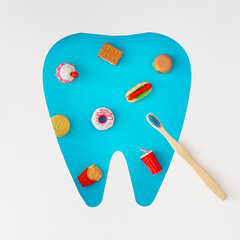 Creative layout made with food products, organic bamboo toothbrush and tooth shaped cutout on blue background. Minimal dental concept. Trendy dentistry idea. Flat lay style. Top view banner.