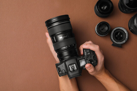 Photographer with professional camera on brown background, top view