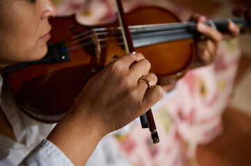 Close-up of a musician's hands playing a violin with focus on strings