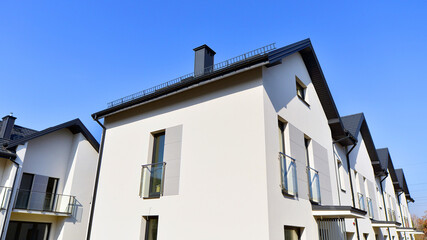 The real estate market in the suburbs. New single family houses in a new development area. Residential homes with modern facade. Terraced family homes in newly developed housing estate. 