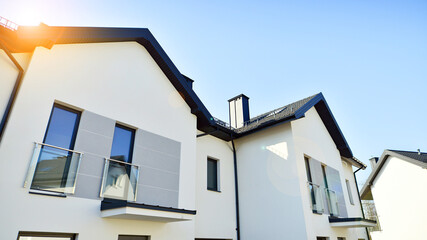 The real estate market in the suburbs. New single family houses in a new development area. Residential homes with modern facade. Terraced family homes in newly developed housing estate. 