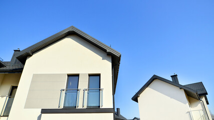 The real estate market in the suburbs. New single family houses in a new development area. Residential homes with modern facade. Terraced family homes in newly developed housing estate. 