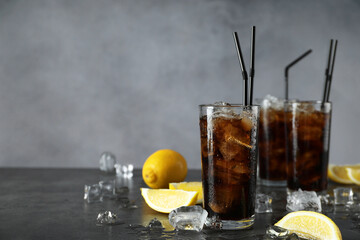 Fresh iced cola and lemon slices on dark grey table. Space for text