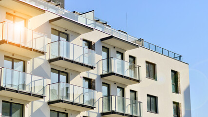 Fototapeta premium Apartment building with symmetrical modern architecture in the city. Modern apartment building on a sunny day. Facade of a modern apartment building. Bottom view. 