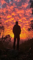 Obraz premium Silhouette of a lone figure admiring a breathtaking sunset spectacle