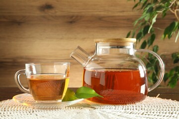 Freshly brewed tea in glass cup and teapot on table