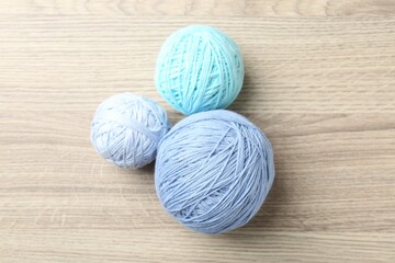 Balls of colorful yarn on wooden table, flat lay