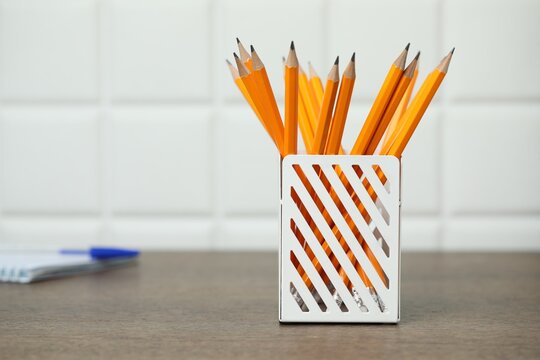 Many graphite pencils in holder on wooden table, space for text - Powered by Adobe