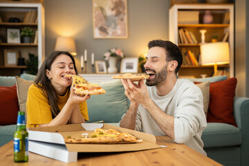 In a cozy living room, a couple shares laughter while enjoying their pizza, highlighting intimacy and joy in each other’s company.