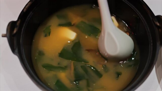 Close up of a woman mixing a miso soup at a restaurant