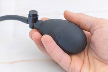 A hand holding an airbrush with a black rubber handle, close-up on the device