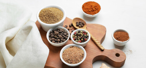Board with different spices on white background