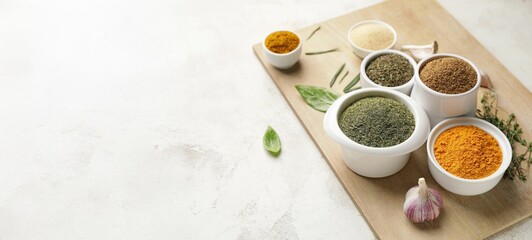 Bowls with different spices on light background with space for text