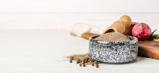 Bowl with black pepper powder on white wooden background