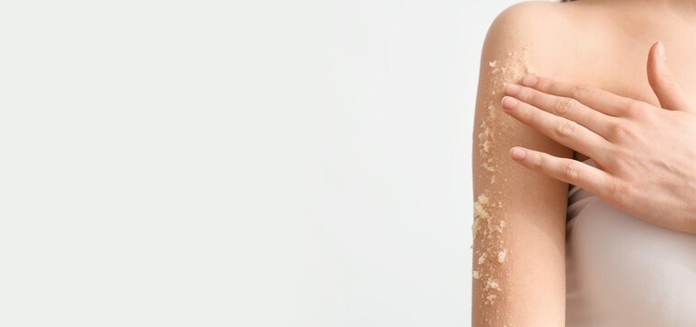 Young woman scrubbing her body against light background with space for text, closeup