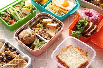 Many lunchboxes with different delicious food on beige tile background