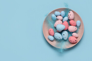 Plate with Easter eggs and feathers on blue background